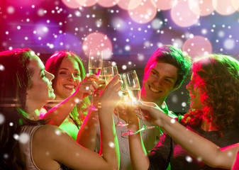 Obraz na płótnie Canvas smiling friends with glasses of champagne in club