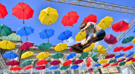 Man in the air on Street decorated with cMan in the air on Street decorated with colored umbrellas