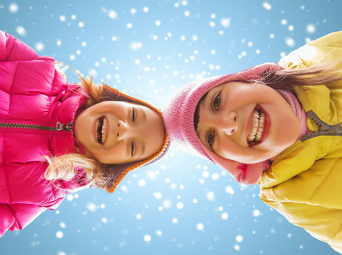 happy little girls faces over blue sky and snow
