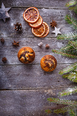 Xmas or new year composition with holiday decoration - Homemade christmas cupcakes, sliced dried oranges on wooden background with spruce twigs and pinecones. Christmas card. Space for text