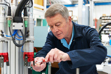 Engineer Working On Machine In Factory