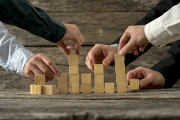 Hands of five businessman holding wooden blocks placing them int