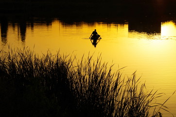 silhouette of a fisherman on a background of city sunset