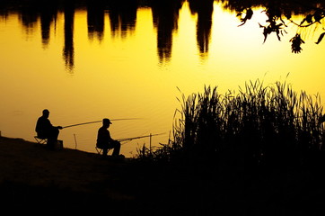 Fototapeta na wymiar Fishermen silhouettes at sunset
