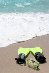 Conceptual snorkeling and swimming gear on beach sand