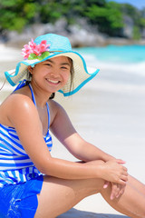 Girl in a blue swimwear sitting a happy on the beach with the sea as background during summer at Koh Miang Island, Mu Ko Similan National Park, Phang Nga province, Thailand