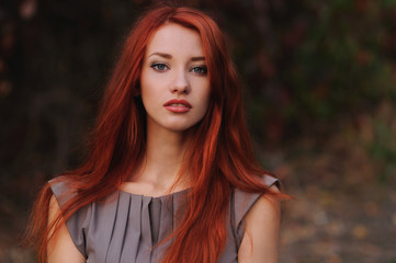 Outdoors portrait of beautiful young woman with red hair