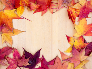 Naklejka na ściany i meble Frame of autumn leaves on wooden board: background with room for text