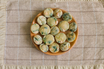 Muffins with salmon, spinach and cheese in big orange plate on center beige linen tablecloth. Aerial view.