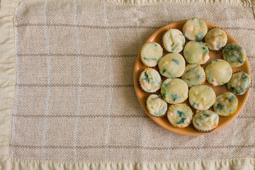 Obraz na płótnie Canvas Muffins with salmon, spinach and cheese in big orange plate on center beige linen tablecloth. Aerial view.