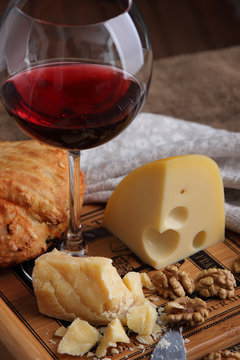 A glass of wine, hard, aged cheese and nuts..