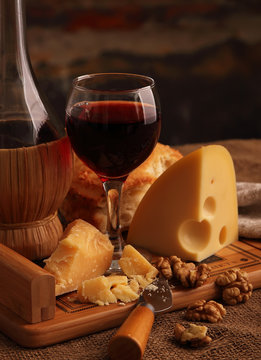A glass of wine, hard, aged cheese and nuts..