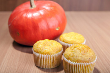 Three cupcakes and pumpkin on wood texture table