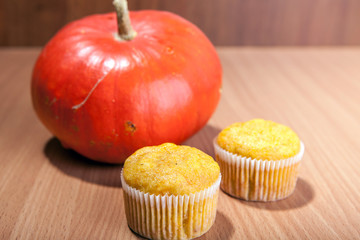Two cupcakes and pumpkin on wood texture table