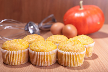 Six cupcakes, pumpkin and baking kitchenware on wood texture table
