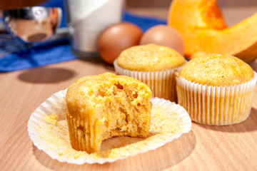 Bite-off cupcake, pumpkin and baking kitchenware on table