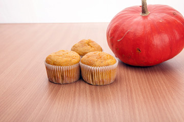 Three cupcakes and pumpkin on wood texture table