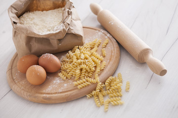 Raw homemade pasta and ingredients for pasta on wooden background