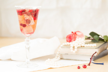 Glass of champagne and cranberry cocktail with vintage books and