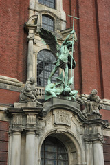 Fototapeta na wymiar A religious sculptural composition. Bronze statue of the Archangel Michael is located above the main portal of the St. Michael's Church in Hamburg.