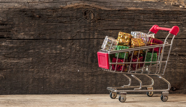 trolley cart with gift boxes over wooden background