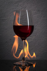 Glass. Red wine glass  with fire splash in front of stone granit