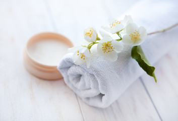 Fototapeta na wymiar face cream with jasmine blossom and towel on white wooden table