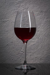 Glass. Red wine glass  in front of stone granite wall