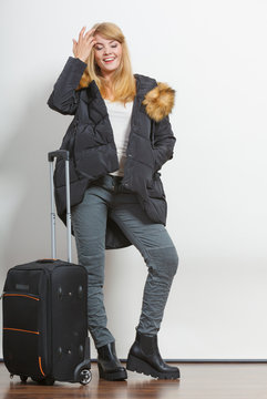 Happy young woman in warm jacket with suitcase.