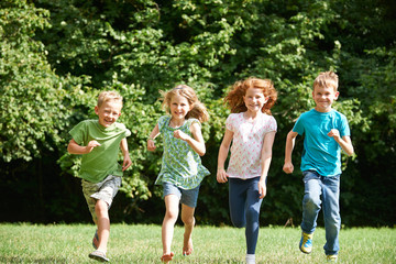 Group Of Happy Children Running Towards Camera Through Field