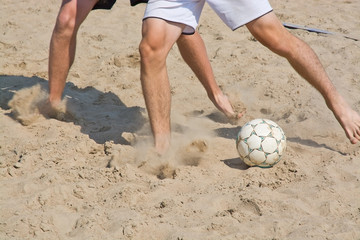 Beach soccer leg closeup and ball with soft sand speed cloud