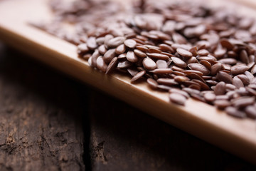 Flax seeds on a wooden plate on a wooden table. Closeup..