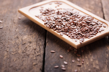 Flax seeds on a wooden plate on a wooden table.