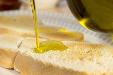 Pouring Extra Virgin olive oil on a slice of toasted bread. Mediterranean breakfast