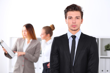 Cheerful business man in office with colleagues in the background, sturt  up team