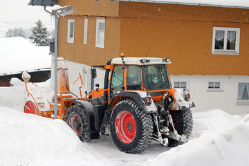 Obraz na płótnie Canvas Schneeräumarbeiten mit Traktor und Schneefräse