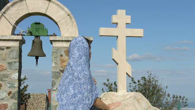 Religious woman looking at stone cross with hope. Symbol of church, religion