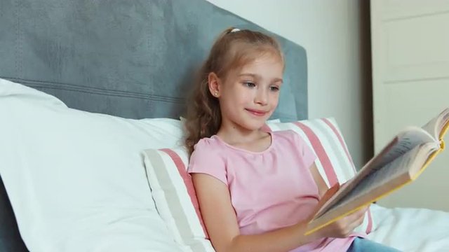 Portrait girl reading a book and hugging it and smiling at camera