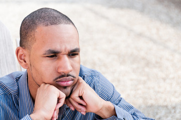 Portrait of Serious, Young, Handsome Black Man Deep in Thought with Scowl and Chin Resting on...