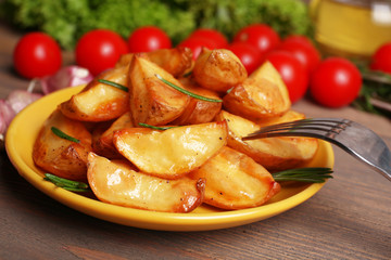 Baked potato wedges on wooden table, closeup