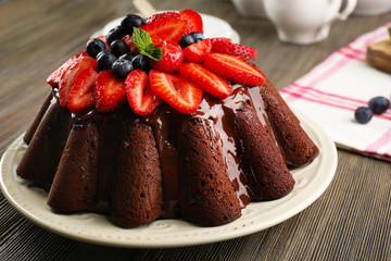 Delicious chocolate cake with berries in plate on table, closeup