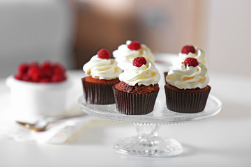 Beautiful chocolate cupcakes with cream and raspberry on table