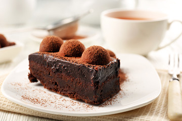 Slice of chocolate cake with a truffle on plate closeup