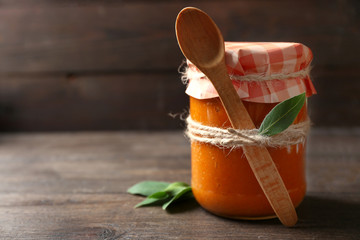 Jar with squash caviar on wooden background