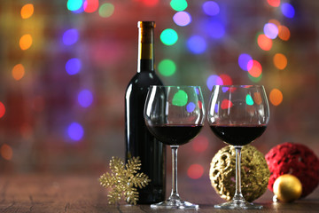 Red wine and Christmas ornaments on wooden table on Christmas lights background