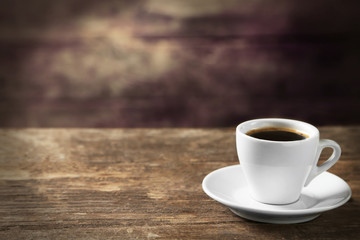 Cup of coffee and coffee grains on wooden background