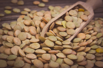 Vintage photo, Heap of green lentil with spoon on wooden background