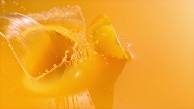 Sliced orange falling into orange juice shooting with high speed camera.