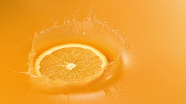 Sliced orange falling into orange juice shooting with high speed camera.
