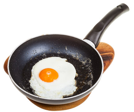 one fried egg in black frying pan isolated